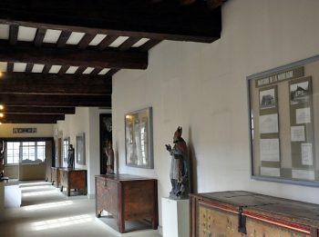 Couloir de l'ancien couvent aménagé avec meubles et statues